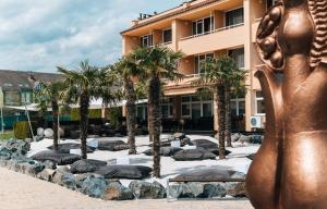a statue in front of a building with palm trees at Belenus Thermalhotel superior in Zalakaros