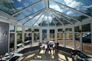 Portree Guest House في بورتري: حديقة شتوية مع سقف زجاجي مع طاولات وكراسي