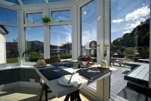a conservatory with a table and a large window at Portree Guest House in Portree