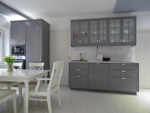 una cocina con armarios grises y una mesa y sillas blancas. en Dorothy Apartman, en Siófok