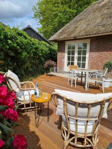 a wooden deck with chairs and a table and a house at B&B Onderderietenkap in Heerde
