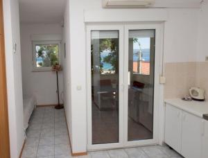 - une cuisine avec une porte coulissante en verre dans l'établissement Studio apartment in Duce with sea view, balcony, air conditioning, WiFi 132-5, à Duće
