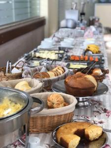 uma linha de buffet com muitos tipos diferentes de pastelarias em Hotel Caverá em Alegrete