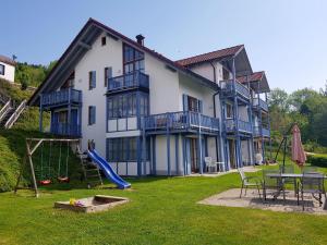 une grande maison avec une aire de jeux dans la cour dans l'établissement Ferienwohnung 32 im Ferienland Sonnenwald - Bayerischer Wald, à Schöfweg