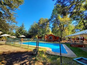 a swimming pool in a park with a fence at Cabañas Bordenieve in Las Trancas