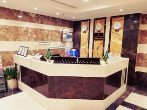 a lobby with a counter with clocks on the wall at فندق الركائز in Makkah
