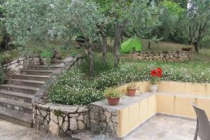 d'un jardin fleuri, d'un mur en pierre et d'escaliers. dans l'établissement Poggio House, tranquillità e comfort nella natura, à San Casciano in Val di Pesa
