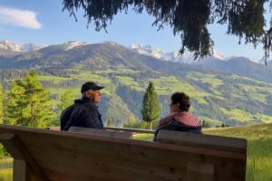 un hombre y una mujer sentados en un banco mirando las montañas en Haus Pinter in Schladming - Dachstein Region en Pruggern