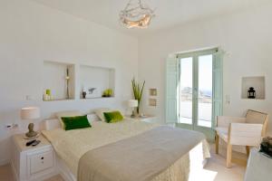 a white bedroom with a large bed with green pillows at Black Rock in Akrotiri