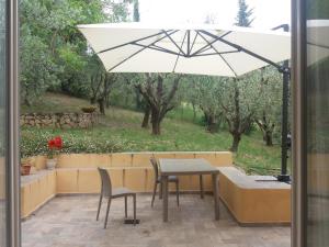 une terrasse avec une table, des chaises et un parasol dans l'établissement Poggio House, tranquillità e comfort nella natura, à San Casciano in Val di Pesa
