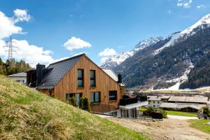 ein Haus auf einem Hügel mit Bergen im Hintergrund in der Unterkunft DER WOLF -Suiten in Sankt Anton am Arlberg