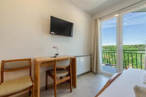 a room with a desk and a tv and a balcony at Bed & Breakfast Maki in Biograd na Moru