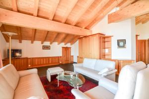 a living room with white furniture and wooden ceilings at Casa Arturo Penthouse in Riederalp