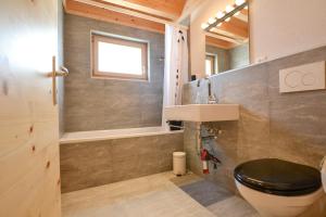 a bathroom with a toilet and a sink and a tub at Hirschfluh Duplex in Riederalp