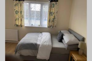 a bedroom with a bed and a window with curtains at A beautiful modern home close to Central London in Goodmayes