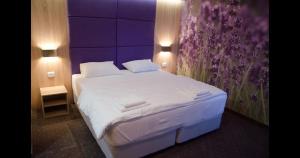 a bedroom with a white bed with a purple wall at villa pergola in Trebinje +9 photos