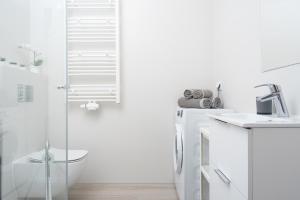 a white bathroom with a shower and a sink at Apartament SEA HOLIDAY in Kołobrzeg