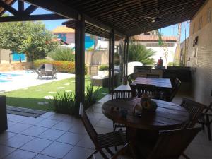 Un patio al aire libre con una mesa y sillas de madera. en Casa Praia dos Carneiros, en Praia dos Carneiros