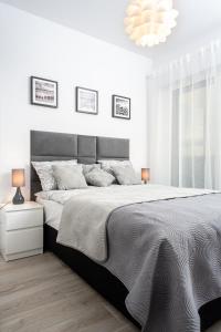 a white bedroom with a large bed and a chandelier at Apartament SEA HOLIDAY in Kołobrzeg