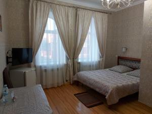 a bedroom with two beds and a tv and curtains at Готель "Монастирський" in Putyvlʼ