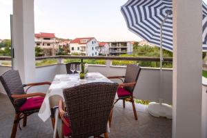 a table and chairs on a balcony with an umbrella at APARTMANI IVAN I RUŽA in Lopar