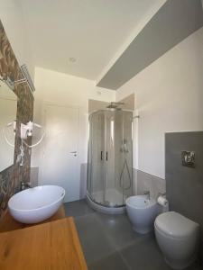 łazienka z 2 umywalkami, prysznicem i 2 toaletami w obiekcie La Via del Mare w mieście Licola