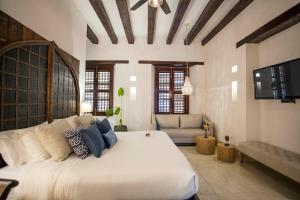 a bedroom with a large white bed and a couch at Casa Gastelbondo in Cartagena de Indias