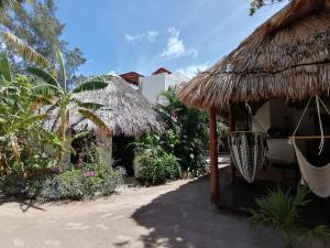 ein Haus mit einer Strohhütte und einer Hängematte davor in der Unterkunft Casa Mech in Holbox