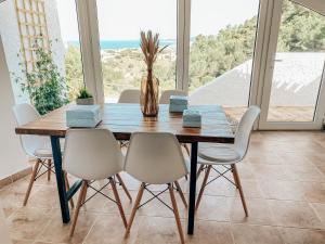 a dining room with a wooden table and white chairs at Montgo Home in Jávea +47 photos