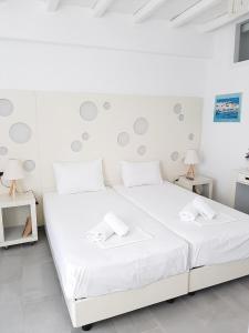 uma cama branca num quarto branco com 2 candeeiros em Chaniotis Studios em Kalafati
