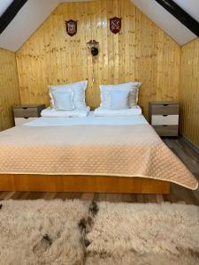 a bedroom with a large bed with wooden walls at Pensiunea Casa Cezara in Silvaşu de Jos