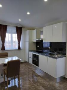 a kitchen with white cabinets and a table and a counter top at Apartmani Delač in Vodice