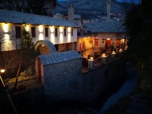 a building with lights on the side of it at night at Hotel-Restaurant Kriva Ćuprija in Mostar