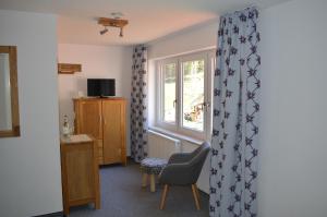 ein Wohnzimmer mit einem Stuhl und einem Fenster in der Unterkunft Bergsteiger-Hotel "Grüner Hut" in Bad Hindelang