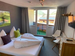 Cette chambre d'hôtel comprend un lit et un balcon. dans l'établissement Bergsteiger-Hotel "Grüner Hut", à Bad Hindelang