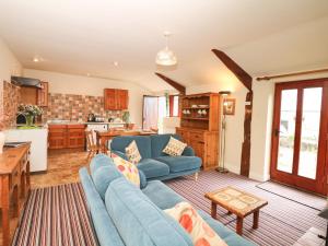 a living room with a blue couch and a kitchen at The Shippen in Northleigh