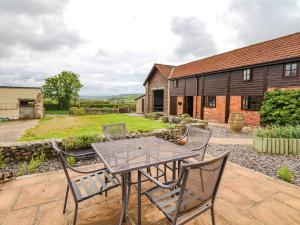 a patio with a table and chairs and a house at The Shippen in Northleigh