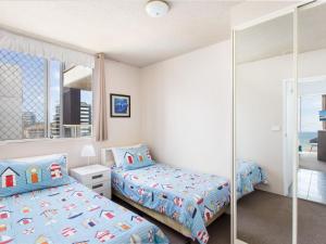 a bedroom with two beds and a mirror at Ebbtide 22 in Forster