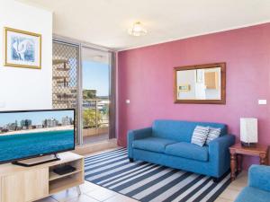 een woonkamer met een blauwe bank en een tv bij Ebbtide 6 in Forster