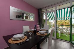 a dining room with a black table and a pink wall at Duplex in Playa De Las Américas-center in Playa de las Americas