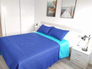 een slaapkamer met een blauw bed en een witte muur bij Ca L´Ana in Tazacorte