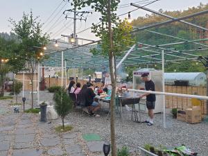 un grupo de personas sentadas en una mesa en un jardín en Sky Vivaldi Pension en Hongcheon