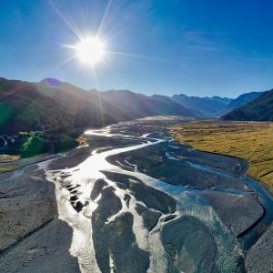 an aerial view of a river with the sun in the sky at Arthur's Pass Ecolodge in Cass