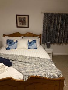 1 dormitorio con 1 cama con almohadas azules y blancas en Holcot Cottage 