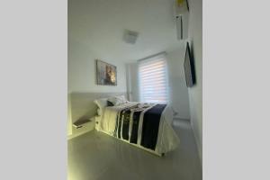 a white bedroom with a bed and a window at Luxury casa vacacional por días -mes bien dotada in Cali