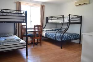 a room with two bunk beds and a table at Busselton Ithaca Motel in Busselton