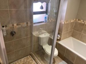 a bathroom with a shower with a toilet and a tub at Unit 14 A-Block Bains Game Lodge in Bloemfontein