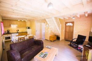 ein Wohnzimmer mit einem Sofa, einer Küche und einer Treppe in der Unterkunft Chalet des Noisettes in Murol + 5 Fotos