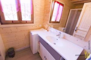 ein Badezimmer mit einem weißen Waschbecken und einem Spiegel in der Unterkunft Chalet des Noisettes in Murol