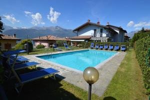 une piscine avec des chaises bleues et une maison dans l'établissement Casa delle Corti, à Colico